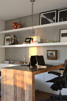 a desk with a laptop on top of it in front of a book shelf filled with books