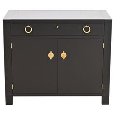 a black and white cabinet with two gold knobs on the front door, one drawer open