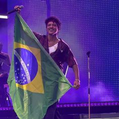 a man holding a brazil flag on stage