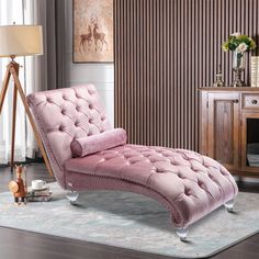 a pink chaise lounge chair sitting on top of a rug in a living room