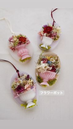 three pieces of glass with flowers in them on a white tablecloth covered table top