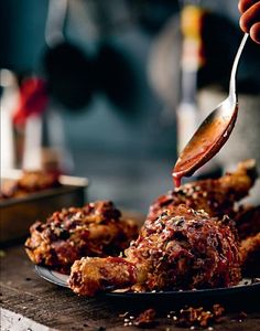 a person is dipping sauce on some meat in a plate with other food items behind them