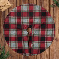 a red and black plaid christmas tree skirt on a wooden surface with presents around it