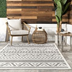 two chairs and a table in front of a wall with wood planks on it