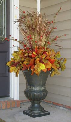 a vase filled with lots of flowers sitting on top of a stone floor next to a door