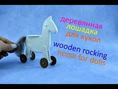 a hand is holding a toy horse with wheels on the blue background that says wooden rocking horse for dolls