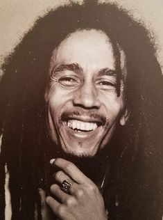 a black and white photo of a smiling man with dreadlocks