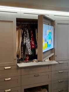 an open closet with clothes on hangers and a flat screen tv in the corner