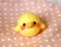 a small yellow bird sitting on top of a pink and white polka dot covered blanket