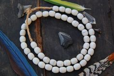 two white beads and some feathers on a table