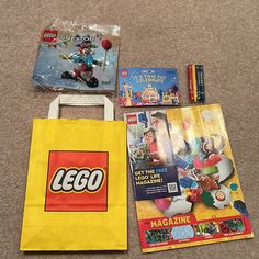 various lego products are laid out on the floor, including a yellow bag and magazine