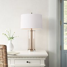 a white lamp sitting on top of a table next to a vase with flowers in it