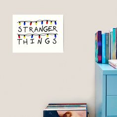 there is a poster that says strange things on the wall next to a blue dresser