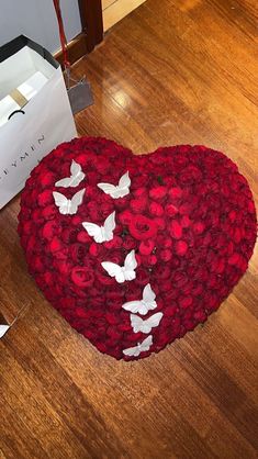 a heart shaped box with flowers and butterflies on the floor next to a card board