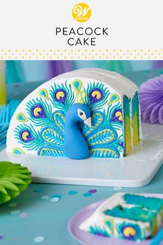 there is a peacock cake on the table with blue and purple decorations around it,