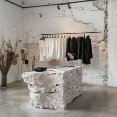 a clothing store with white brick walls and clothes on racks