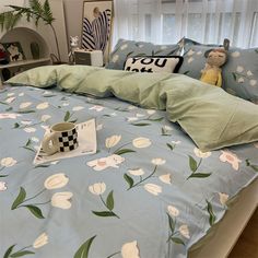 a bed with blue and white flowers on the comforter next to a coffee cup