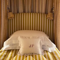 a bed with two pillows on top of it next to a curtained headboard