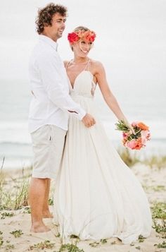 a man and woman standing on top of a beach next to each other holding hands