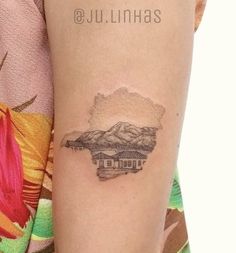 a woman's arm with a tattoo on it that has mountains in the background