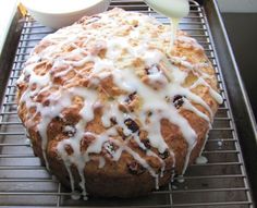 a loaf of bread with icing sitting on a cooling rack