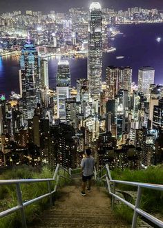 a man standing on top of a set of stairs in front of a city at night