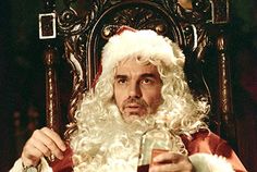 a man dressed as santa claus sitting in a chair holding a beer and looking at the camera