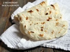 two floured flatbreads sitting on top of a white towel next to a wooden table