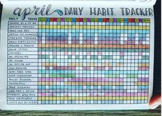 a hand holding up a paper with an image of the daily habit tracker on it