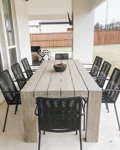 an outdoor dining table with chairs and a bowl of fruit on the outside patio area