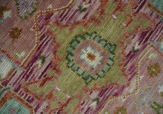 an old rug with many different colors and patterns on the carpet, including pinks, green