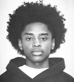 a black and white photo of a young man with curly hair wearing a hoodie