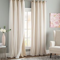 a living room filled with furniture and a window covered in white drapes next to a chair