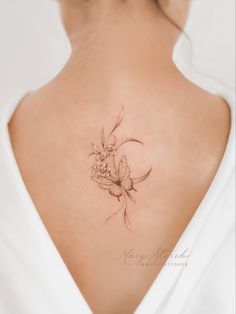 the back of a woman's neck with a flower tattoo on it