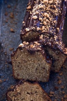 there is a loaf of cake with chocolate frosting and nuts on the top slice