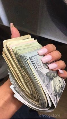 a woman's hand holding stacks of money