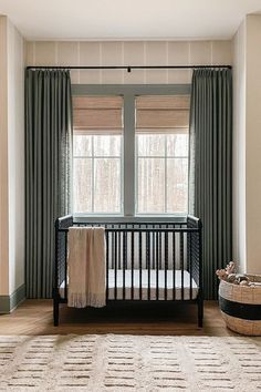 a baby crib in the corner of a room with two windows and a rug on the floor