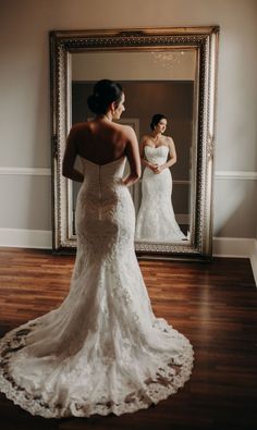 a woman in a wedding dress looking at herself in the mirror with her reflection behind her