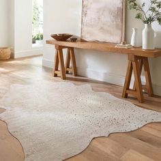 a wooden table sitting next to a white rug on top of a hard wood floor