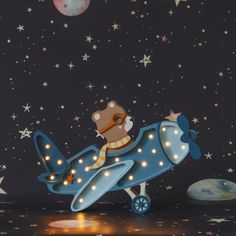 a teddy bear riding on top of an airplane in the night sky with stars and moon