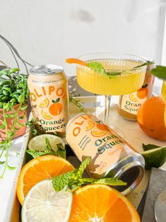 oranges, lemonade and other drinks are arranged on a tray with flowers in the background