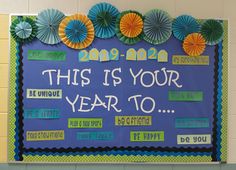 this is your year to bulletin board with paper fan decorations on it in the classroom