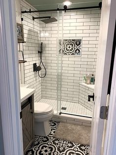 a bathroom with black and white tiles on the floor, shower stall and sink area