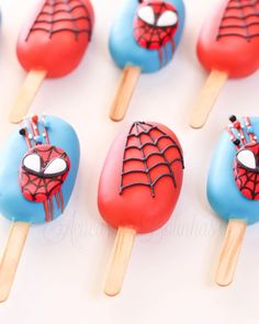 spiderman lollipops are on sticks with blue and red frosting in the shape of pops