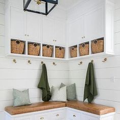 a white bench sitting under a window next to a wooden counter top with baskets on it