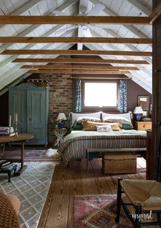 an attic bedroom with exposed ceilings and wood flooring is furnished with wicker furniture