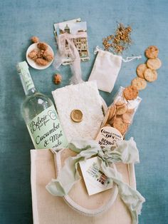 an assortment of snacks and wine on a blue tablecloth next to a white bag