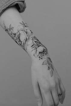 a woman's arm with flowers on it and a hand holding the wrist tattoo