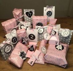 many wrapped presents are sitting on the floor with tags and numbers around them, all decorated in pink and black