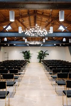 an empty room with black chairs and chandelier hanging from the rafter ceiling